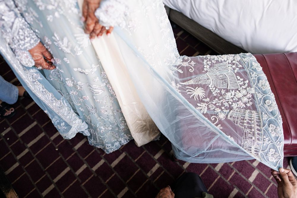 Embroidered bridal train held open to show beaded landmark motifs before the ceremony
