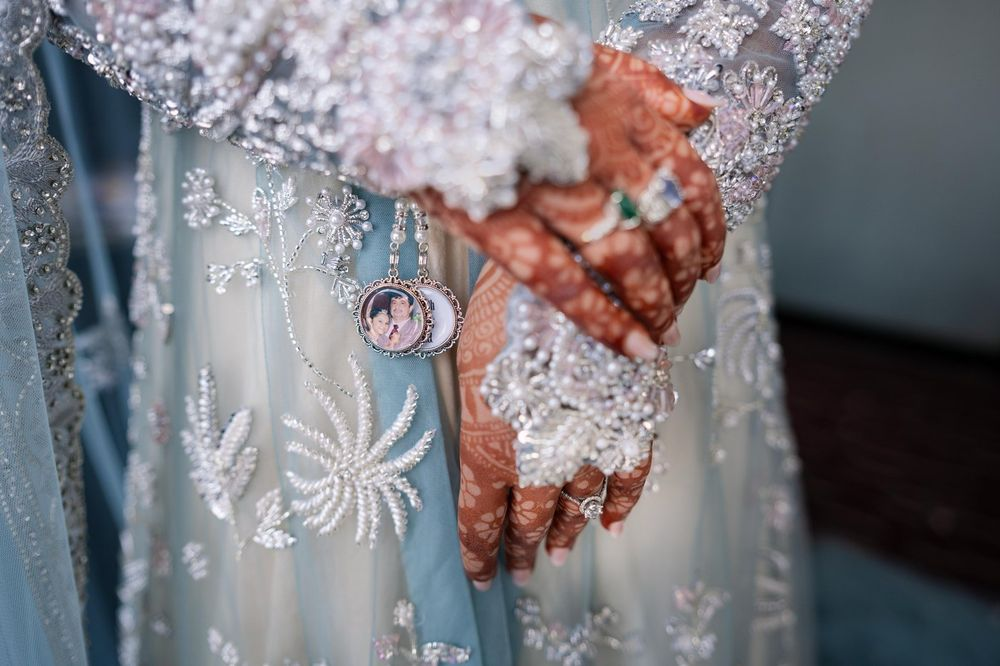 Family photograph keepsake charm pinned among pearl and bead handwork on a bridal outfit