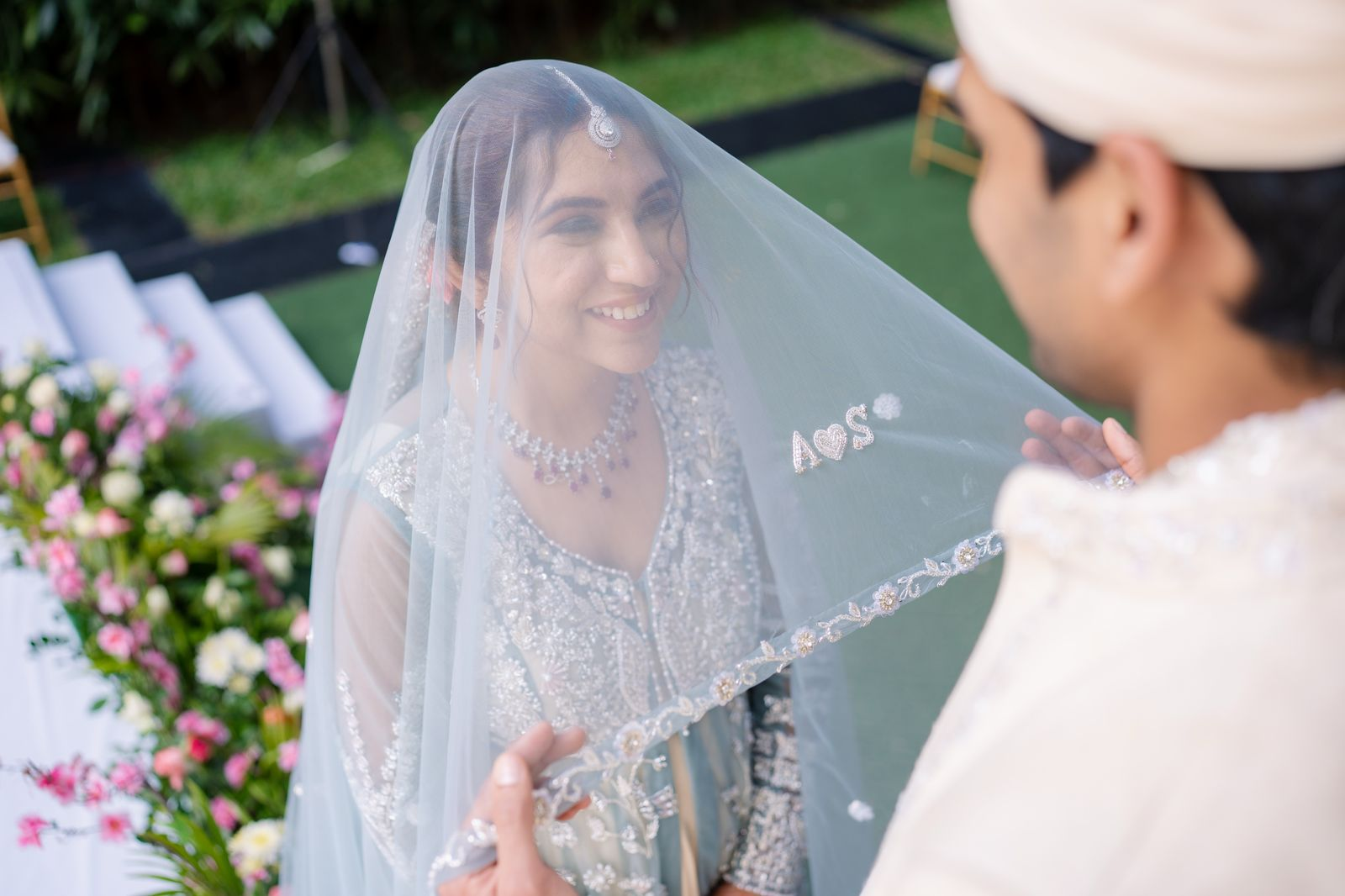 Bride smiling beneath a personalised silver wedding veil during her ceremony