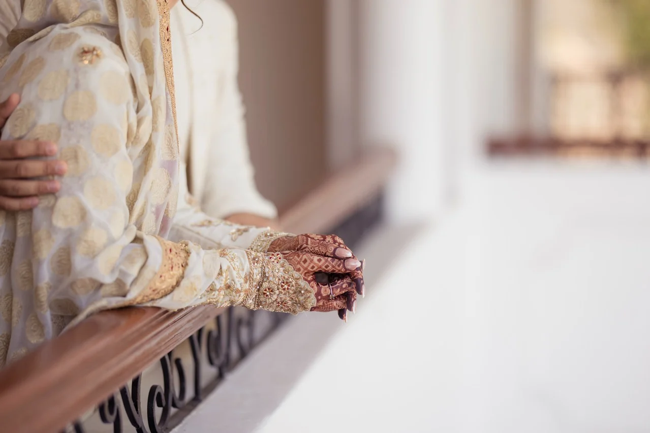 Ivory bridal sleeve with hand embroidery and mehendi detail on a sunlit balcony