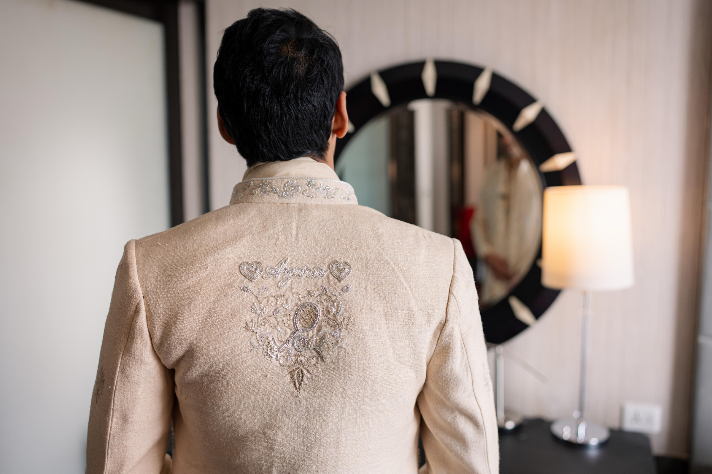 Groom in an ivory jacket with personalised hand embroidery and beadwork across the back