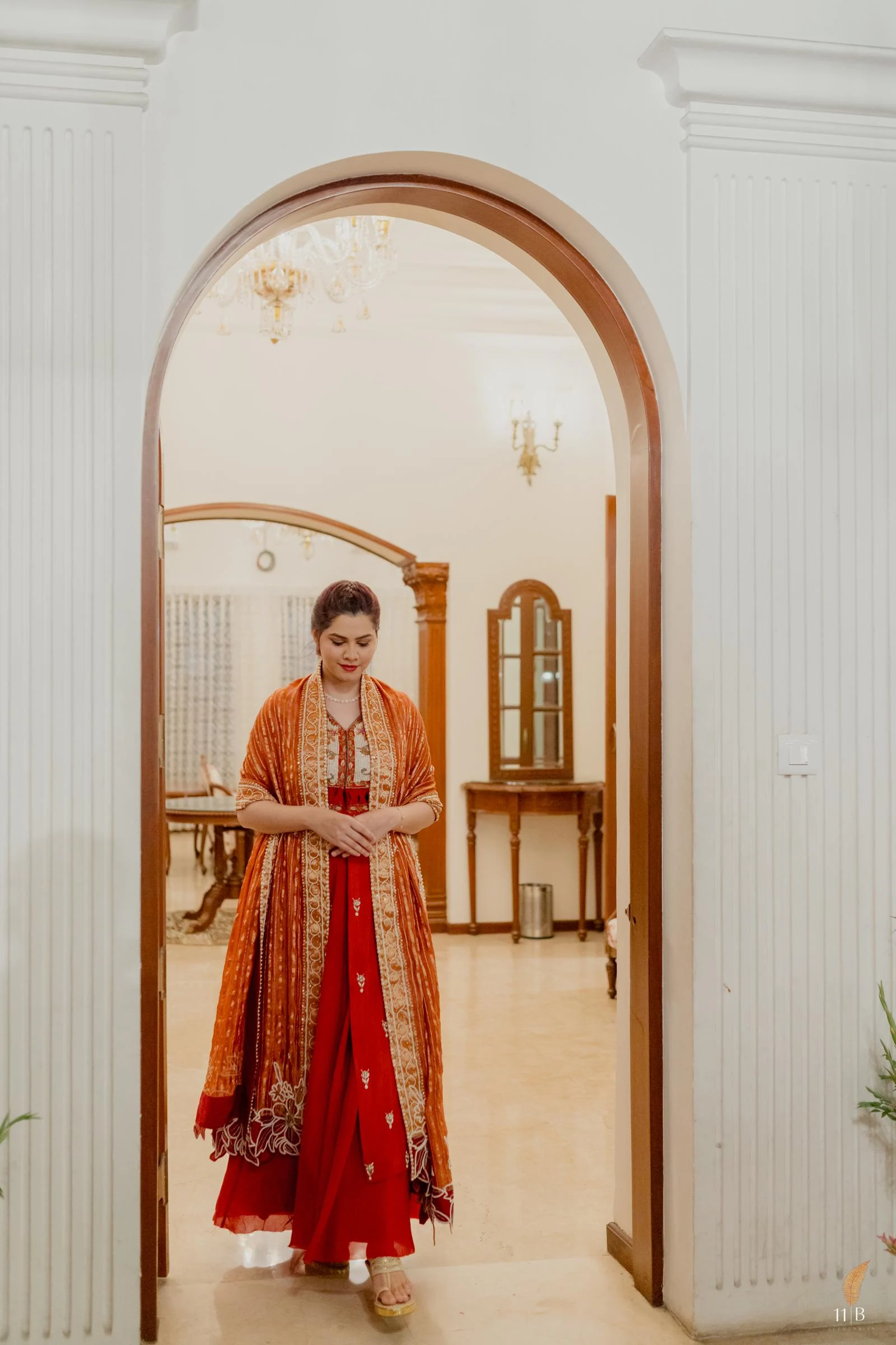 Bride in red Gulnaz Amin weddingwear framed by an atelier arch