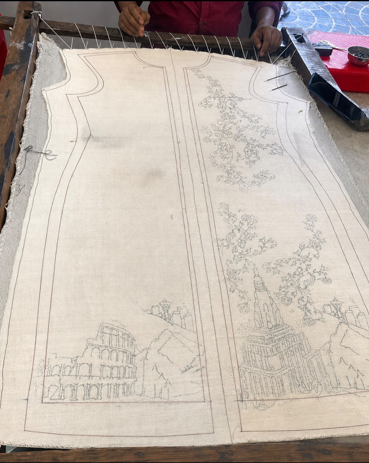 Wedding atelier artisan preparing a hand-drawn floral and architectural embroidery pattern